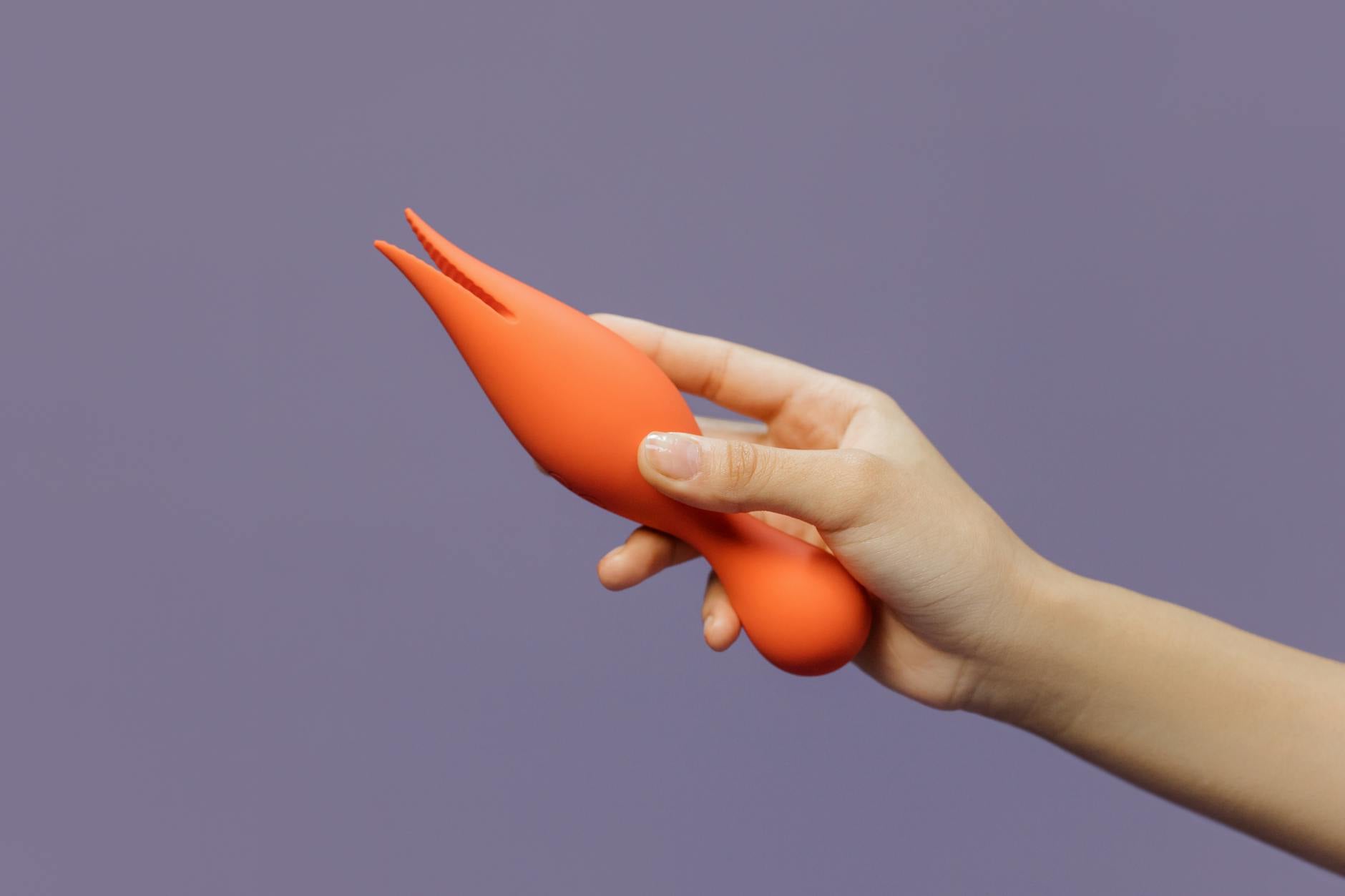 Two hands holding vibrators against a pastel background, representing different pleasure preferences