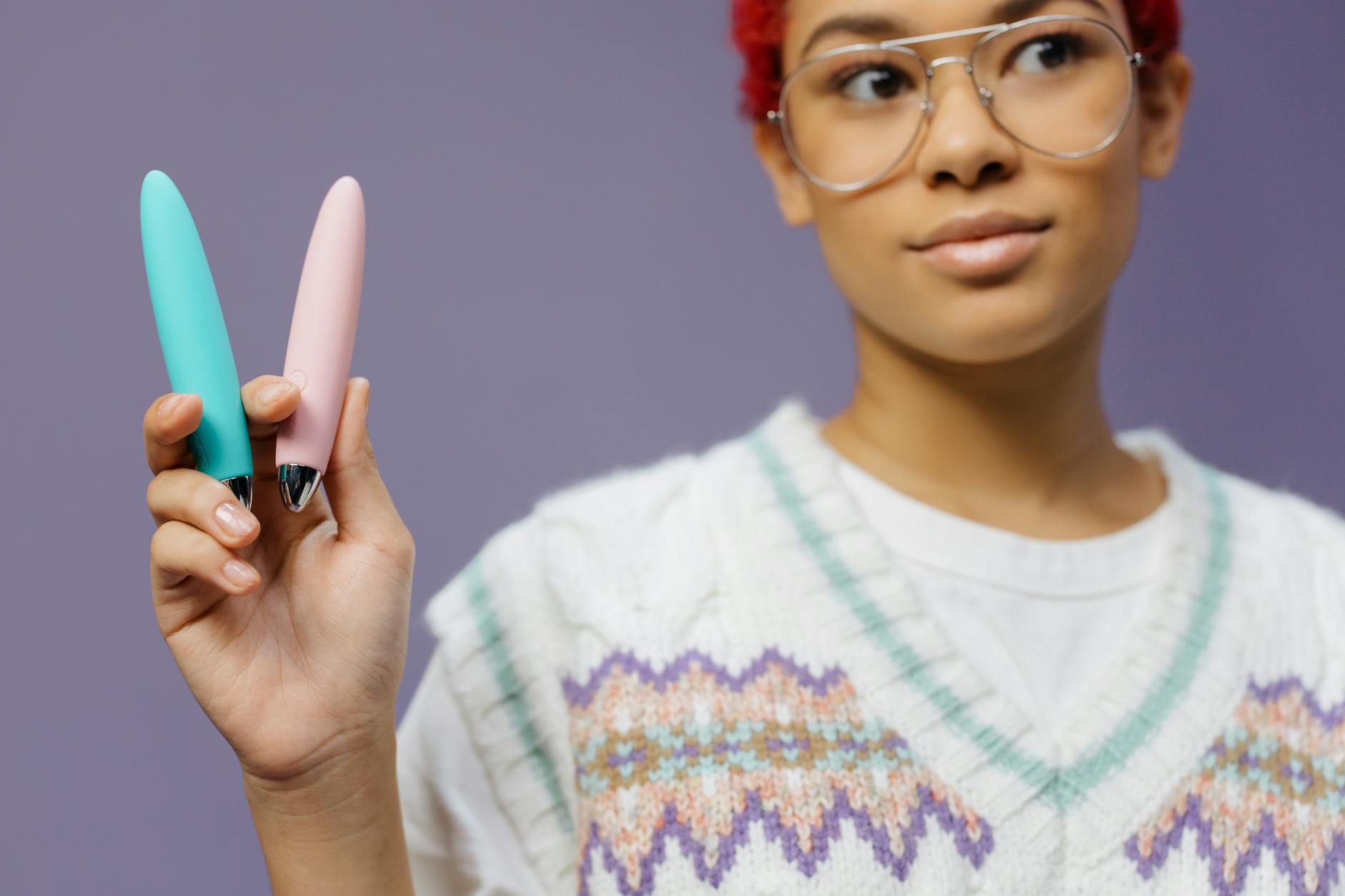 Femme tenant deux vibromasseurs colorés sur fond violet