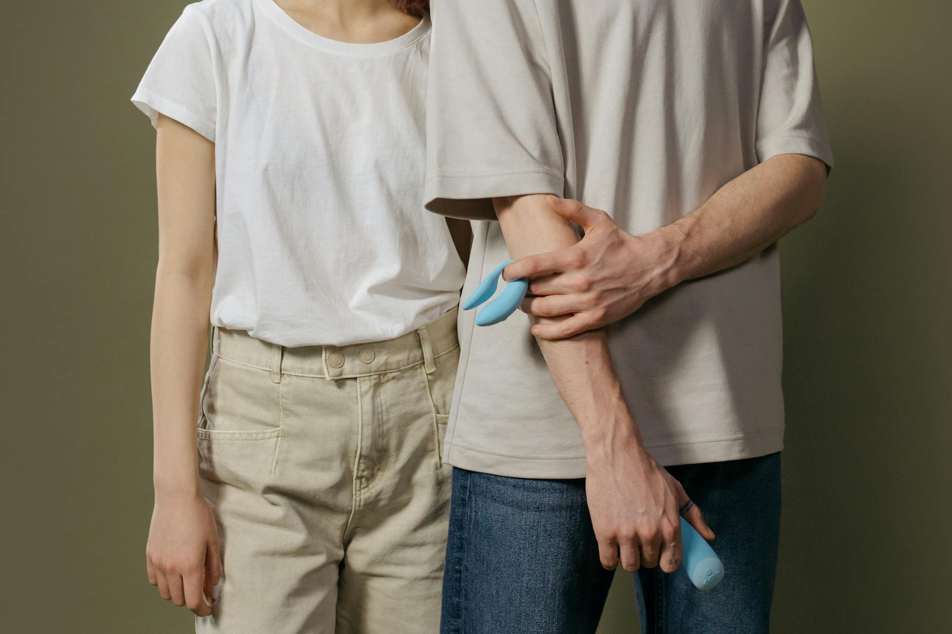 A young couple standing together indoors, discussing intimacy and introducing toys into their relationship.